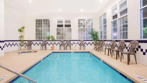 A swimming pool with chairs along the sides and large windows. - Surestay Hotel by Best Western North Myrtle Beach (North Myrtle Beach)