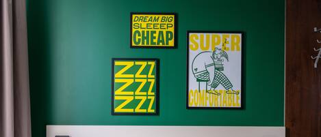 A bedroom with a green wall, a bed with white bedding, and three motivational posters.