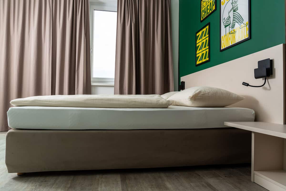 A modern room with a bed, a bedside table, and a wall with artwork.