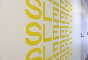 Una pared con la palabra 'SLEEP' repetida verticalmente en grandes letras amarillas.