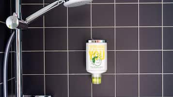 Eine Duschbrause mit Handstrich, eine Flasche Hand- und Körperwaschgel sowie eine geflieste Wand.