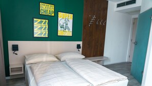 Un dormitorio con una cama, una mesita de noche, un estante en la pared y una puerta.