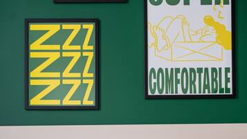 Een slaapkamer met een groene wand, twee ingelijste posters en een bed met wit beddengoed.