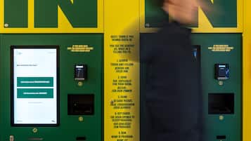Un kiosque d’enregistrement avec des instructions disponibles dans plusieurs langues, un écran affichant la confirmation de la réservation et un clavier permettant de saisir le numéro de chambre.