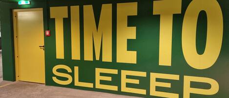 A wall with the text "TIME TO SLEEP" in large letters, a door, and a carpeted floor.