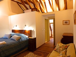 A bedroom with a bed, bedside table, and a wooden ceiling.