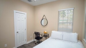 A bedroom with a bed, a desk, a chair, a door, and a window with blinds. - 3br/2ba Remodeled House Near Downtown (San Antonio)