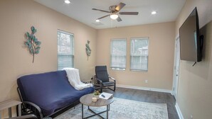 A living room with a blue sofa, a black chair, a coffee table, and a ceiling fan. - 3br/2ba Remodeled House Near Downtown (San Antonio)