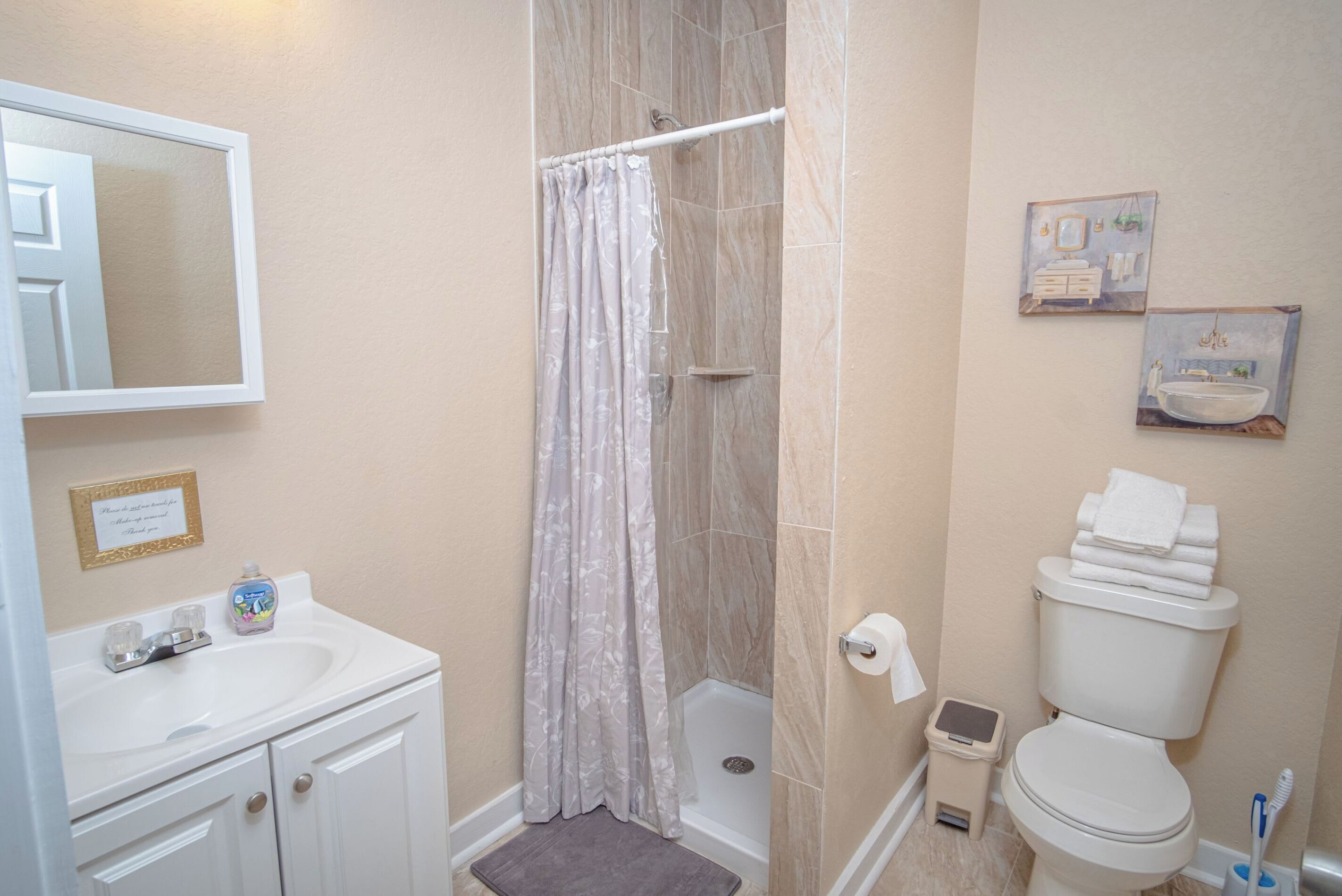 Ein Badezimmer mit Dusche, Toilette, Waschbecken und Spiegel.