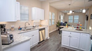 A modern kitchen with white cabinets, granite countertops, and a dishwasher. - 3br/2ba Remodeled House Near Downtown (San Antonio)