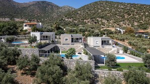 A hillside property with multiple buildings, a swimming pool, and a stone retaining wall. - Family-Friendly villa w/Pool, Children area & BBQ (Vlichada)