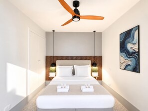 Una habitación de hotel moderna con una cama, ventilador de techo, lámparas de noche y un cuadro en la pared.