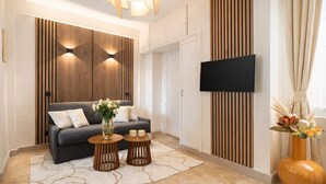 Ein modernes Wohnzimmer mit einer Couch, zwei Beistelltischen, einem Flachbildfernseher und dekorativen Accessoires.