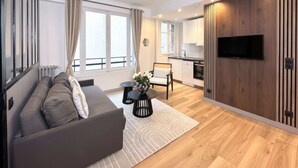 A modern apartment with a living room, kitchenette, and a TV mounted on a wooden wall. - Champs-Elysées - Prestige flat with lift Matignon (Paris)
