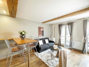 Cozy living space with a dining table, sofa, and shelving unit, perfect for relaxing and reading.