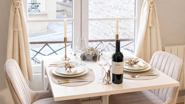 A dining table with two chairs, a candle, wine glasses, and a bottle of wine. - Champs-Elysees stunning family flat (Paris)