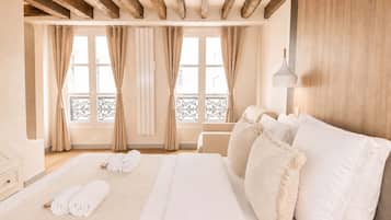 A hotel room with a large bed, wooden beams, a balcony, and a view of the city.