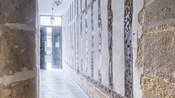 A corridor with stone walls and a tiled floor, leading to a doorway.