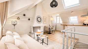 A spacious loft apartment with a high ceiling, a dining area, a kitchen, and a staircase.