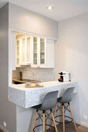 A compact kitchen with marble countertops, two bar stools, and a coffee machine. - Stunning loft for 6 in the 7th district (Paris)