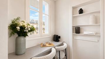 Eine moderne Küche mit einem Fenster, einer Blumenvase, einer Kaffeemaschine und Barhocker.