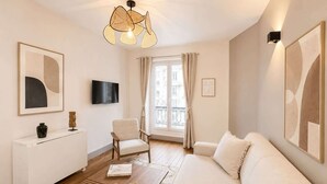 Ein modernes Wohnzimmer mit einer Couch, einem Couchtisch, einem Fernseher und Kunstwerken an den Wänden.