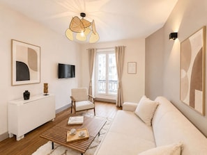 En moderne stue med sofa, sofabord, fjernsyn og billeder på væggene.