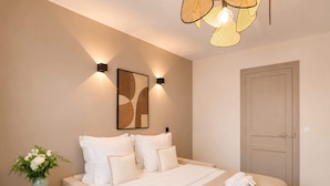 A bedroom with a bed, pillows, a vase with flowers, and a door.