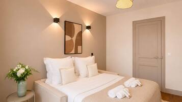 Ein Schlafzimmer mit einem Bett, Kissen, einer Blumenvase und einer Tür.
