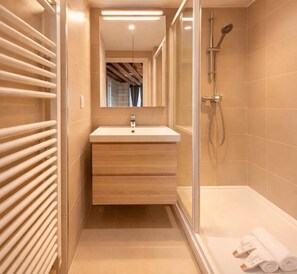 A modern bathroom with a wooden vanity, a glass shower enclosure, and a visible towel rack. - Splendid apartment - Notre Dame Cathedral (Paris)