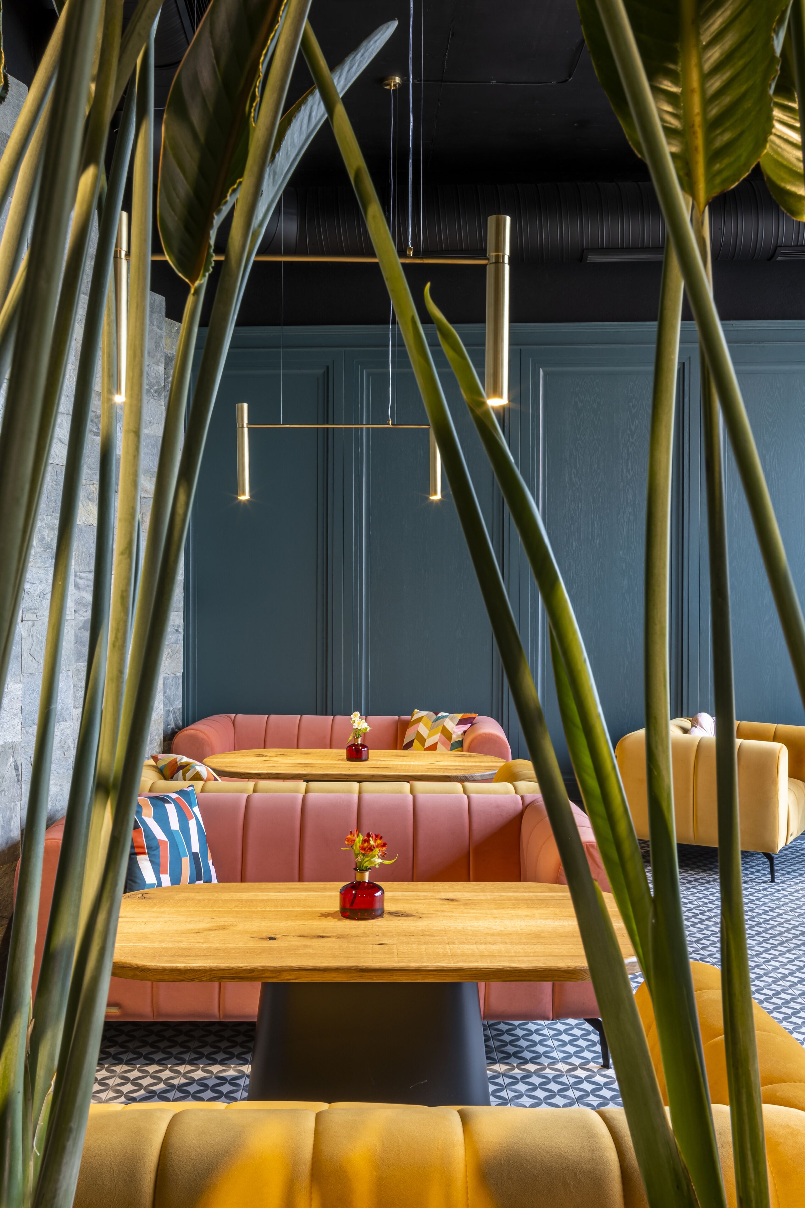 A modern lounge area with a sofa, a wooden table, and a vase of flowers.