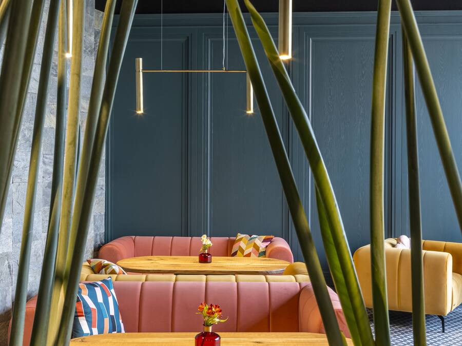 A modern lounge area with a sofa, a wooden table, and a vase of flowers.