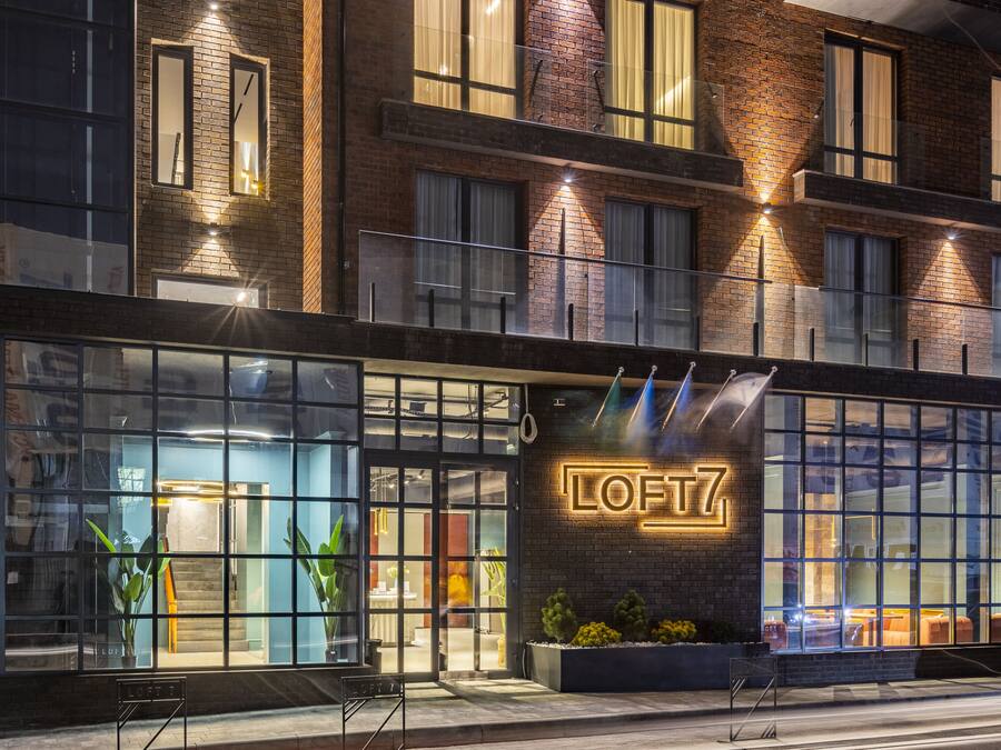 Un edificio moderno con un llamativo letrero que dice "LOFTZ", amplias ventanas y fachada de ladrillo.