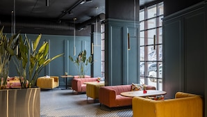 A modern lounge area with seating arrangements, a large potted plant, and a view through large windows.