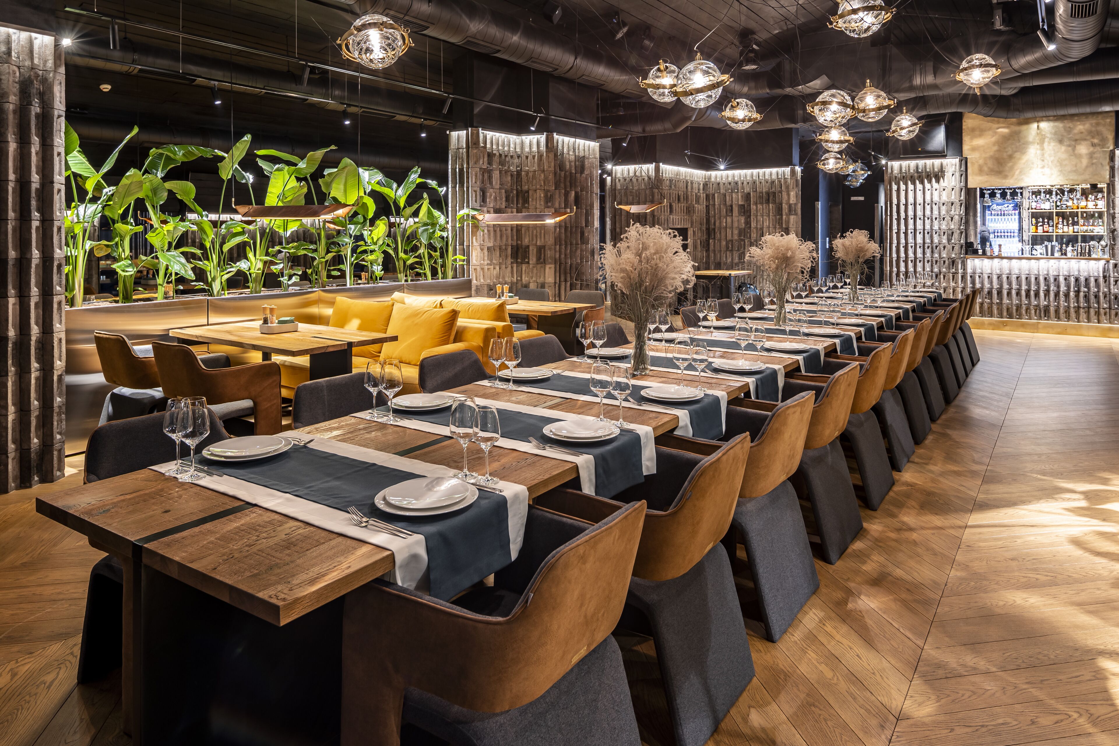 Een restaurant met meerdere eettafels, elk voorzien van borden, bestek en wijnglazen.