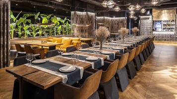 Een restaurant met meerdere eettafels, elk voorzien van borden, bestek en wijnglazen.