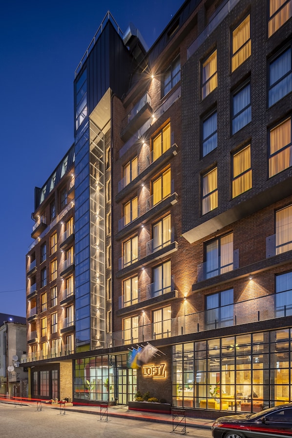 A multi-story hotel with a modern design, featuring large windows and a visible restaurant or lounge area on the ground floor.