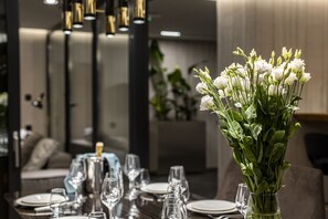 A dining table set with plates, glasses, and a vase of white flowers.