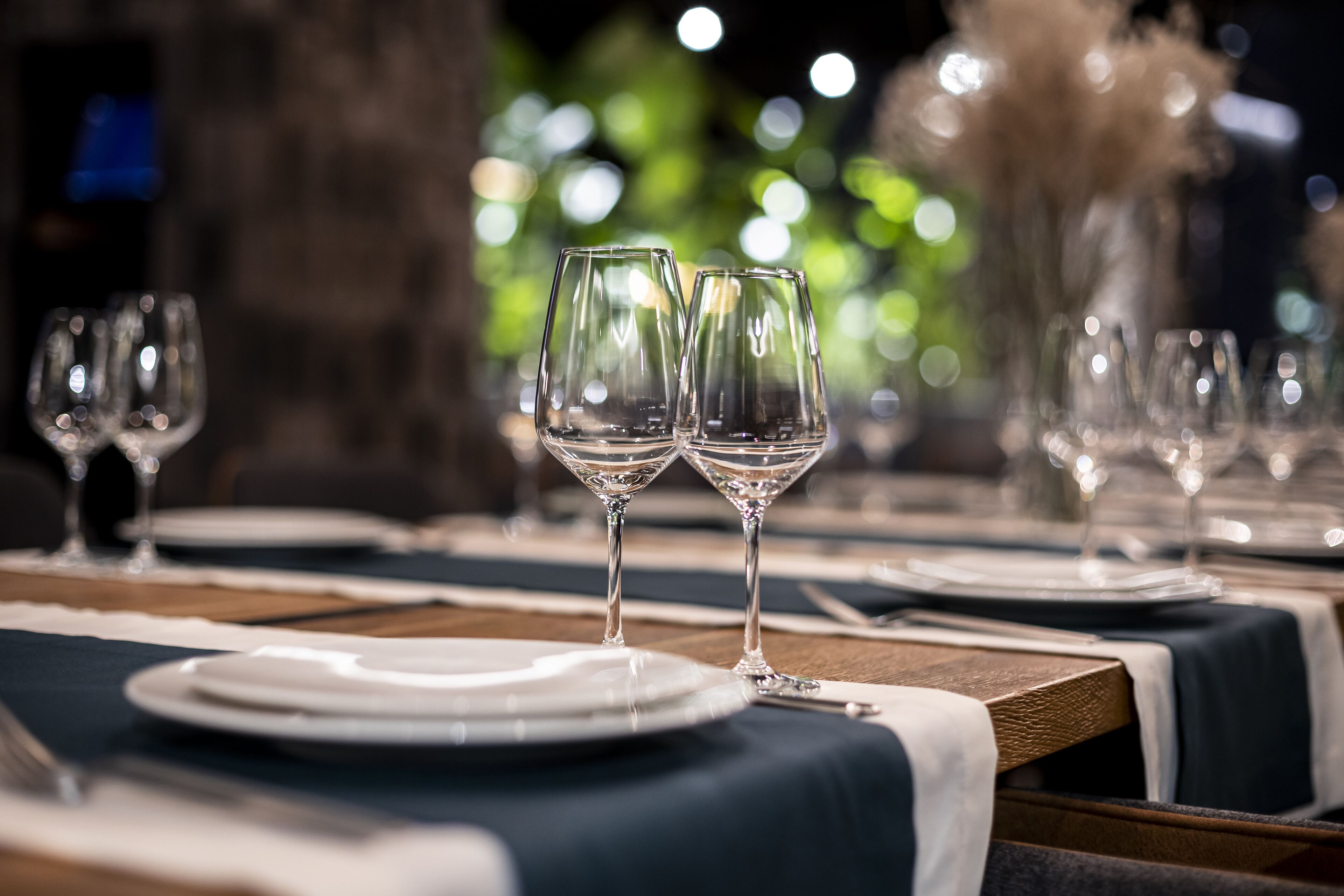 A dining table set with plates, cutlery, and wine glasses.