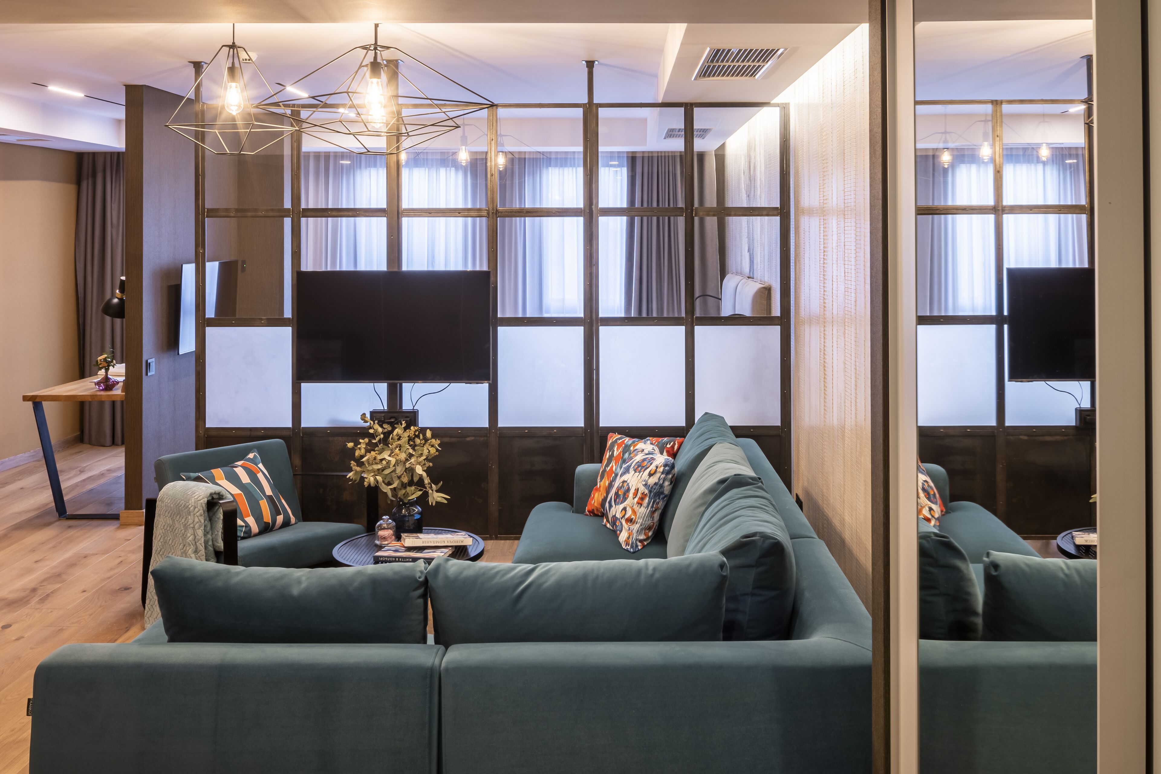 A modern living room with a sectional sofa, a flat-screen TV, and a decorative plant.