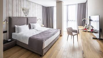 Una habitación de hotel moderna con una cama grande, un escritorio con silla y un televisor.