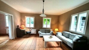 Un salon avec un parquet en bois, deux canapés, une table basse et une lampe.