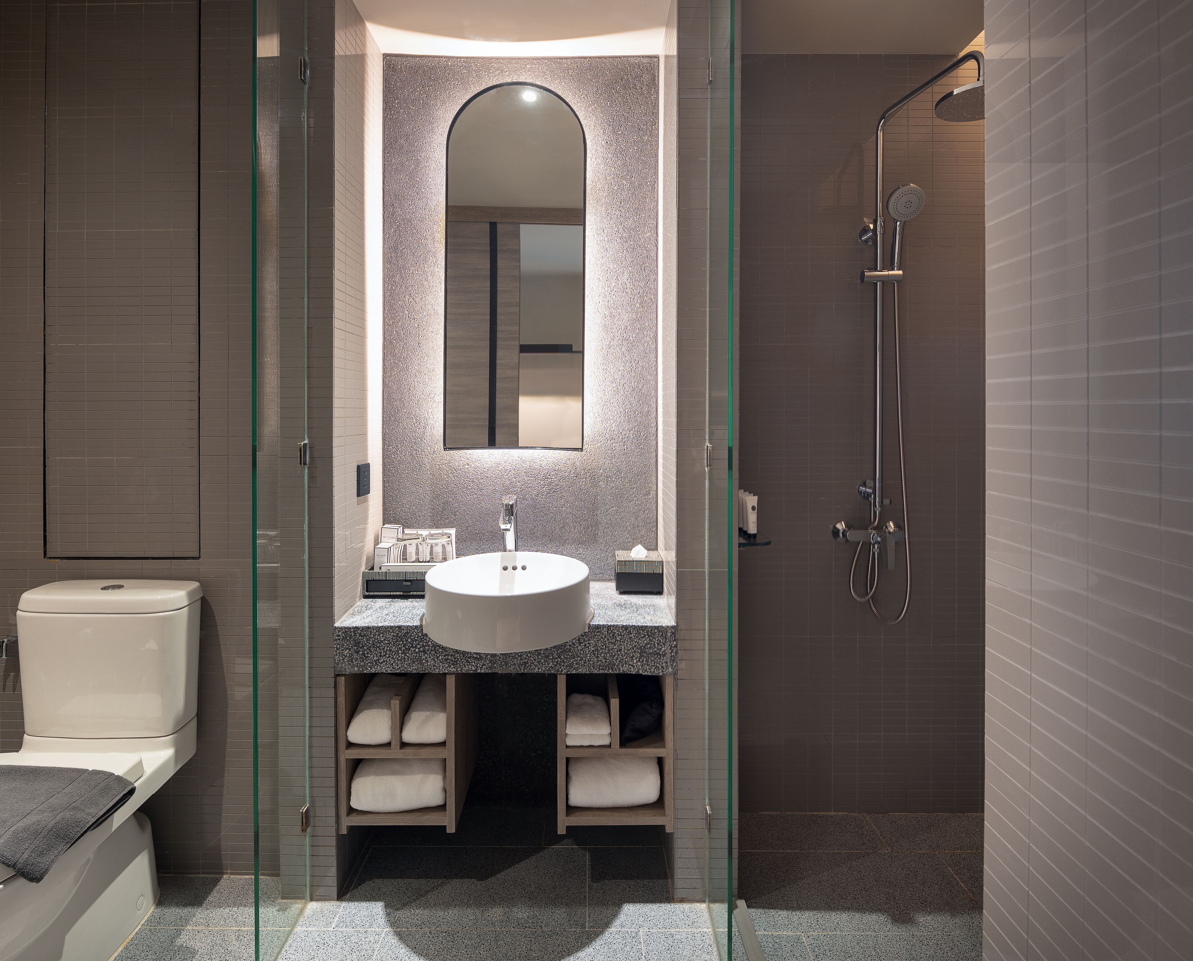 A modern bathroom with a glass-enclosed shower, a round sink, and a mirror above it.