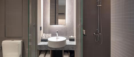 A modern bathroom with a glass-enclosed shower, a round sink, and a mirror above it.