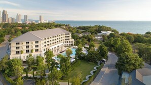 Un hotel grande con varias plantas, piscina y vista al mar.