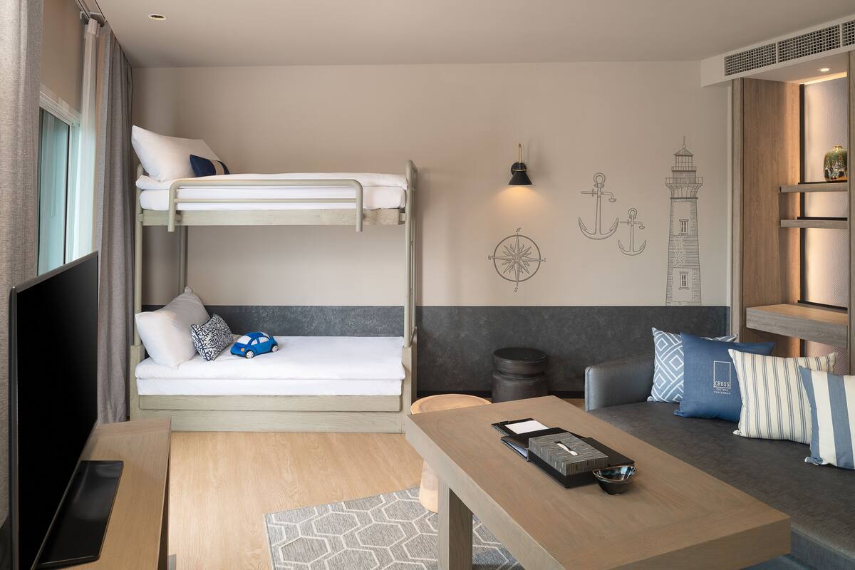 A bunk bed room with a desk and a sofa.