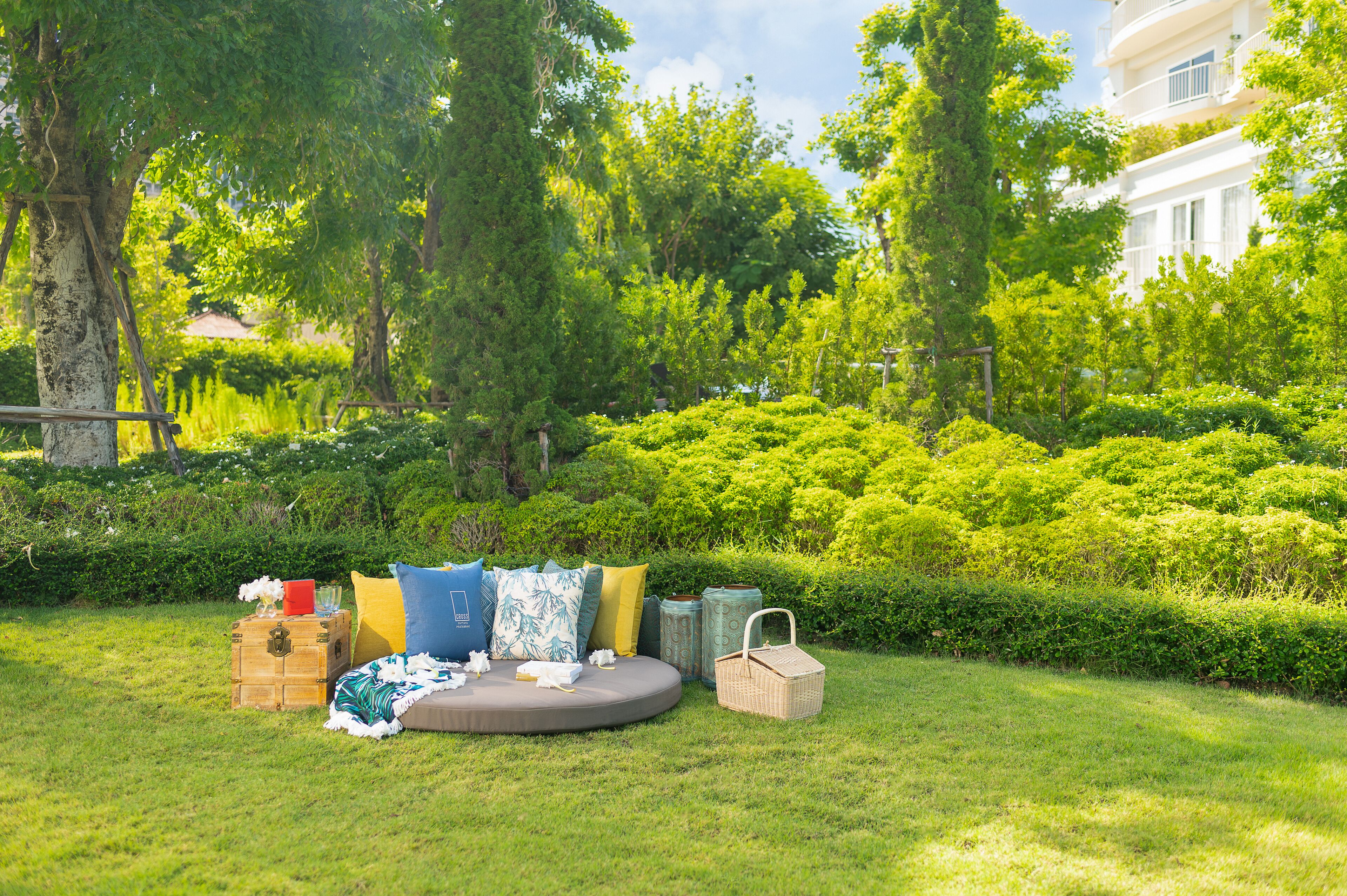 A grassy outdoor area with a circular seating arrangement, surrounded by lush greenery and trees.
