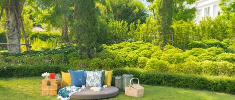 A grassy outdoor area with a circular seating arrangement, surrounded by lush greenery and trees.