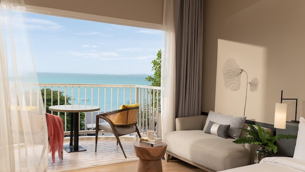 Habitación de hotel con balcón, un sofá, una mesita y una silla.