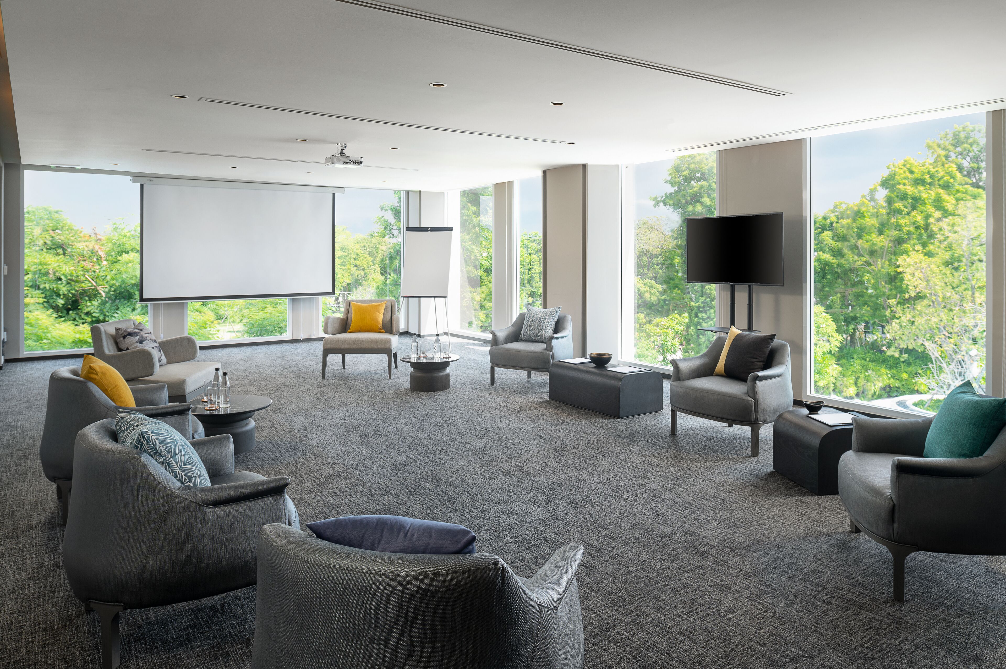 A spacious room with multiple seating areas, a large screen, and a television.